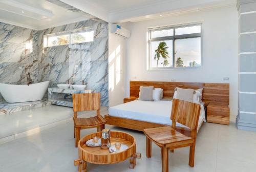 a bedroom with a bed and a tub and a table at Bahari Beach Front Villa in Mdudu Mkubwa