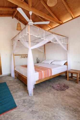 a bedroom with a bed with a mosquito net at Inara Stay in Arugam Bay