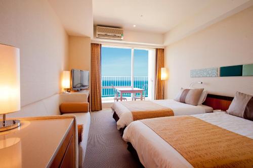 a hotel room with two beds and a television at The Beach Tower Okinawa in Chatan