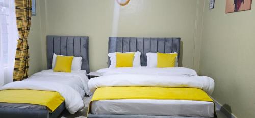 two beds with yellow and white pillows in a room at countrysidegatewayapartments in Nyeri