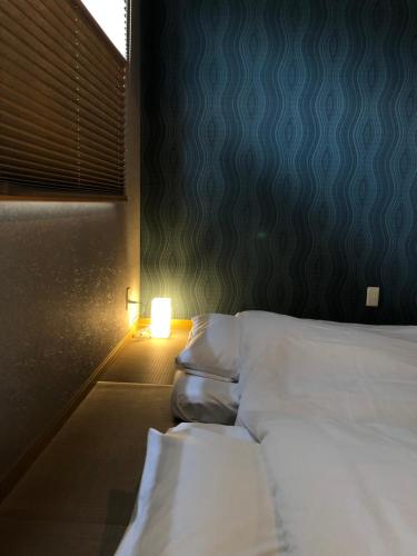 a bedroom with two beds and a light on the wall at Horomachi iori in Kanazawa