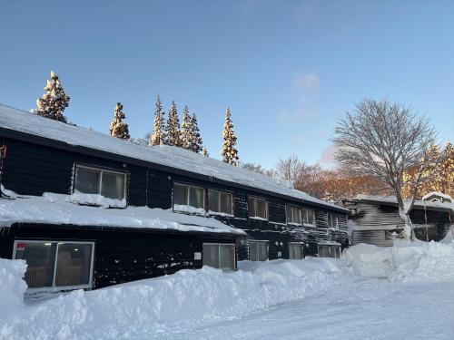 a house covered in snow with a pile of snow at Yachi Onsen in Towada