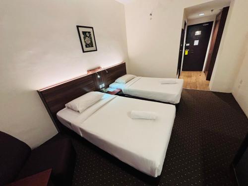 two beds in a hotel room with white sheets at Hotel Yt Midtown Kuala Terengganu in Kuala Terengganu