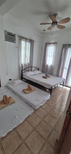 two beds in a room with a ceiling fan at Bohol Panglao Paradise Villa in Panglao Island