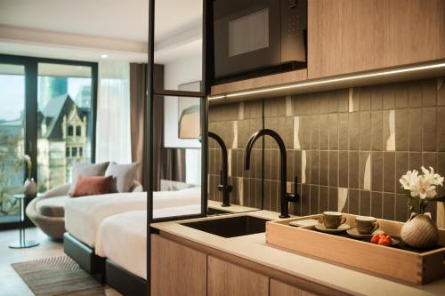 a kitchen with a sink and a bedroom with a bed at Kennedy 89 Hotel Frankfurt, part of Hyatt in Frankfurt