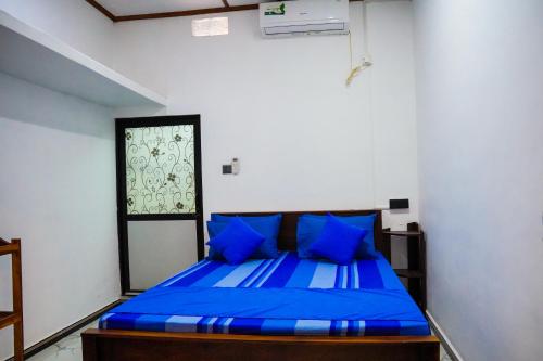 a bedroom with a blue bed with blue pillows at Guru Guest House in Trincomalee