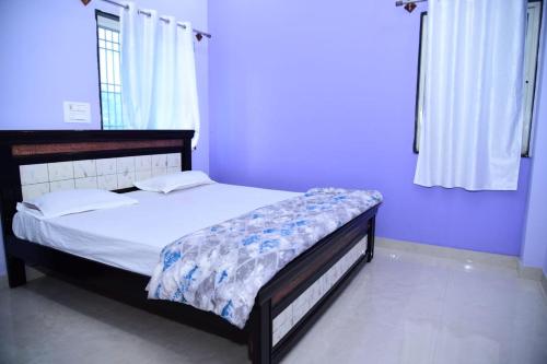 a bedroom with a bed in a purple room at Vasavi Homestay in Mādhavaram