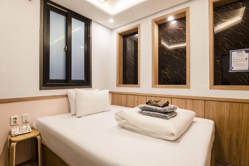 a white bed in a room with windows at Yeongdeungpo Komodo Hotel in Seoul