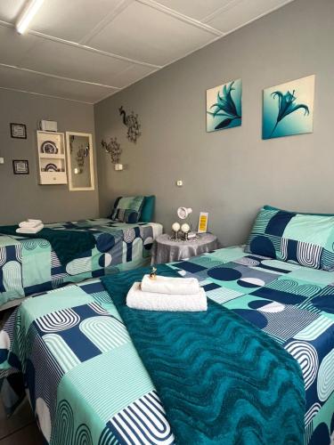 a room with three beds with blue and white sheets at Martinique Guesthouse in Kathu
