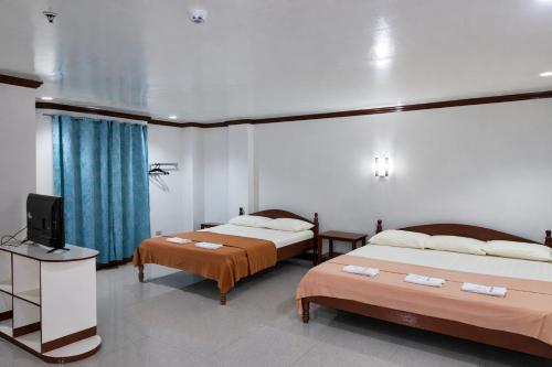 a room with two beds and a television in it at La Elliana Hotel & Restaurant, Inc. in Laoag