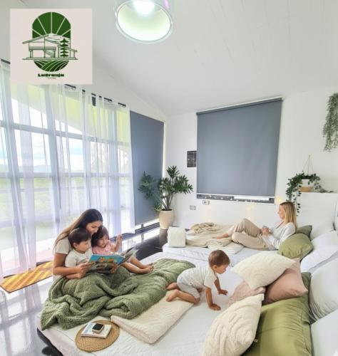 Eine Familie sitzt auf einem Bett im Wohnzimmer. in der Unterkunft La Granja Farmstay Dipolog in Mutia