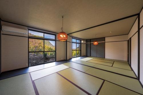 an empty room with large windows in a room with white floors at Umi no SOBA 伊豆 - BBQ & Sauna in Ito