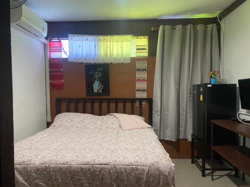 a bedroom with a bed and a desk and a television at Arku’s House in Chiang Mai