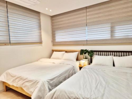two beds in a room with two windows at Cozystay-Beomeo in Hyomoktong-Ilgu