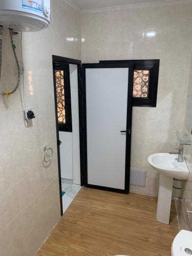 a bathroom with a white door and a sink at Modern studio close to the TER train station in Dakar