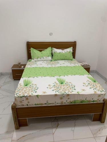 a bed in a bedroom with green and white sheets and pillows at Modern studio close to the TER train station in Dakar