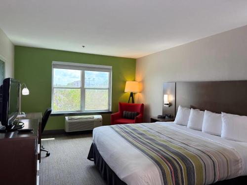 a hotel room with a bed and a red chair at Country Inn & Suites by Radisson, Harlingen, TX in Harlingen