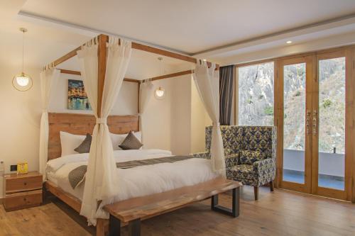 a bedroom with a canopy bed and a chair at Echor Palm Bliss Resort & Spa, Kasol in Kasol