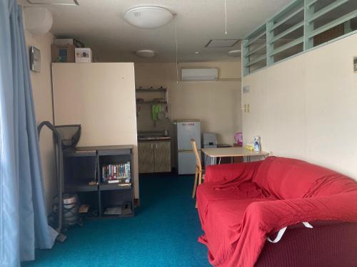 a room with a red bed and a kitchen at BIGJOY INN Hirokouji in Miyako-jima