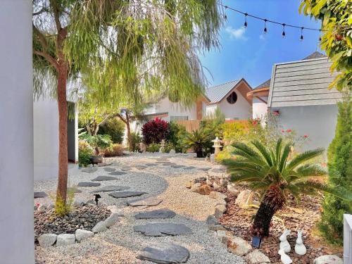 a garden with rocks and a tree and a house at Rabbit Villa Bangsaray in Bang Sare