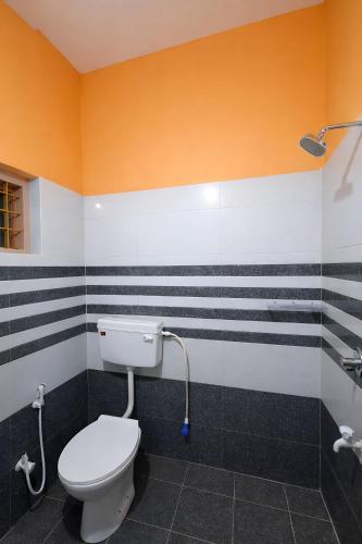 a bathroom with a white toilet and black and white stripes at Casa Tangerina in Varkala
