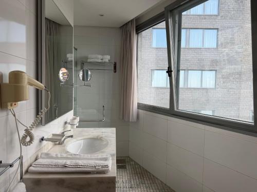 a bathroom with a sink and a window at Maison by Grey Pearls Suites in Mīnāʼ al ‘Atīqah