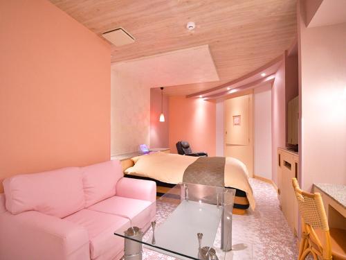 a living room with a couch and a bed at ホテル ヴォーグ in Kuwana