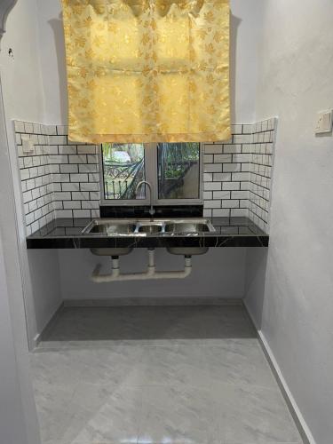a bathroom with a sink and a window at Wan Guest House in Pasir Mas