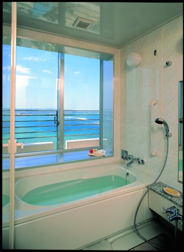 a bathroom with a tub with a view of the ocean at The Beach Tower Okinawa in Chatan