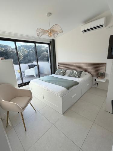 a white bedroom with a bed and a chair at Les hauts de Vaison in Vaison-la-Romaine