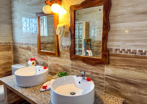 a bathroom with two sinks and a mirror at Coral Apartments in La Digue