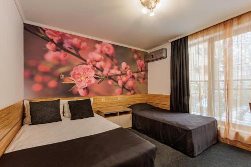 a bedroom with two beds and a painting on the wall at Семеен Хотел Опера in Burgas