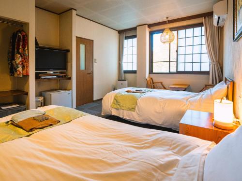 a hotel room with two beds and a tv at Hotaru no Yado Sendou in Yufu