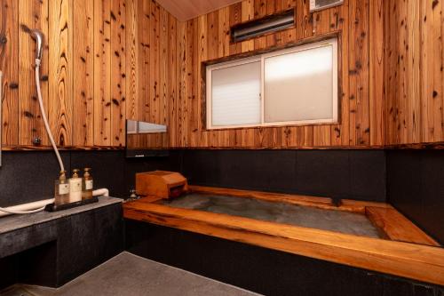 a bath tub in a wooden bathroom with a window at Hotaru no Yado Sendou in Yufu