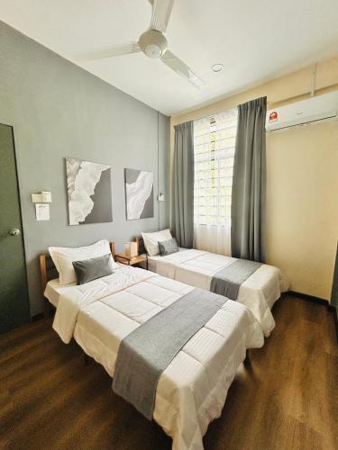 two beds in a hotel room with a ceiling fan at Adwa Guesthouse in Keningau