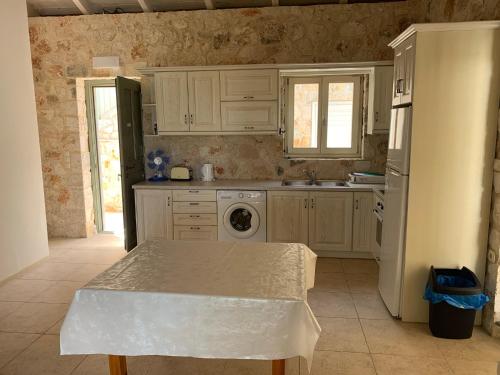 a kitchen with white cabinets and a table in it at Kouvarata Villas Stavros in Vathi