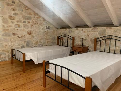 two beds in a room with a stone wall at Kouvarata Villas Stavros in Vathi