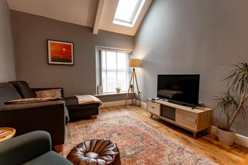 a living room with a couch and a television at Stylish Tenby Apartment, Great Location, Parking in Tenby