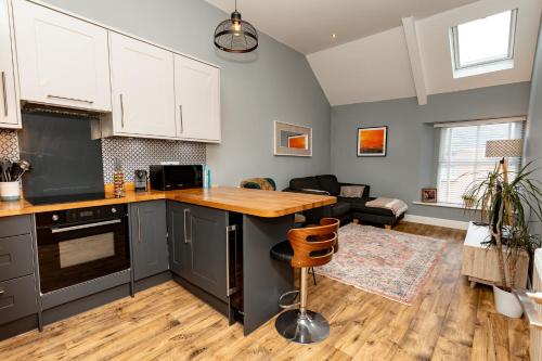 a kitchen with white cabinets and a wooden counter top at Stylish Tenby Apartment, Great Location, Parking in Tenby