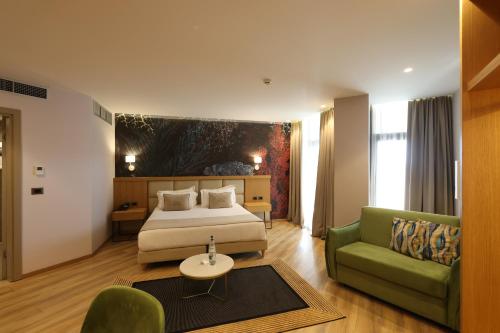 a hotel room with a bed and a green couch at White Hill Hotel, SPA & Conferences in Durrës