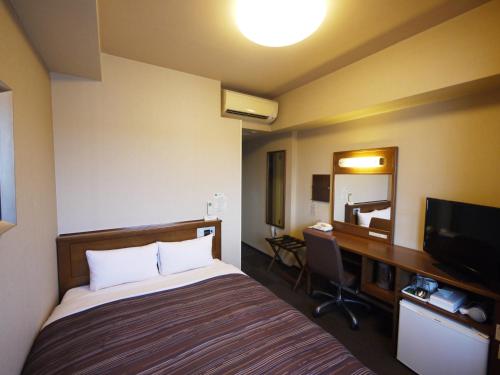 a hotel room with a bed and a desk and a television at Hotel Route-Inn Mito Kencho-mae in Mito