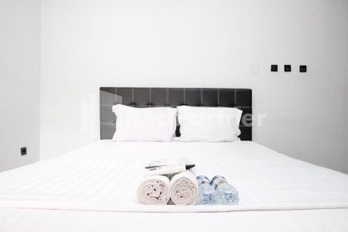 a bed with white sheets and two pairs of shoes at Aster Triplets Guest House JCM Mitra RedDoorz in Yogyakarta