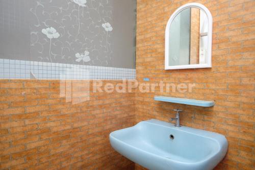 a bathroom with a sink and a mirror on a brick wall at Aster Triplets Guest House JCM Mitra RedDoorz in Yogyakarta