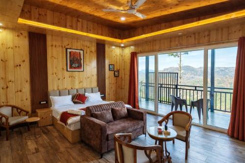 a bedroom with a bed and a couch and a balcony at Pine Country Resort in Mukteshwar