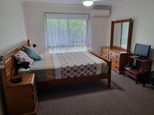 a bedroom with a bed and a dresser and a window at Welcome to Seascapes in Tin Can Bay