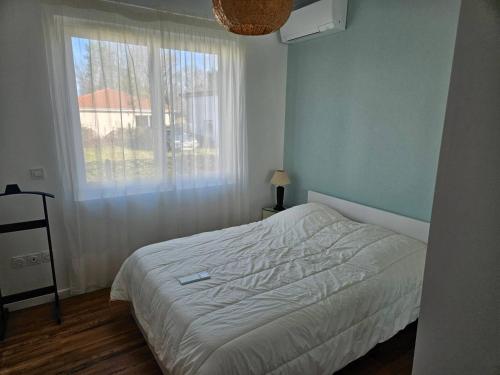 a bedroom with a white bed and a window at La Belle des Pins in Mimizan