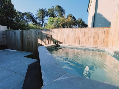 a swimming pool in front of a wooden fence at Hang'Ares, espace unique entre Bassin et Océan in Arès
