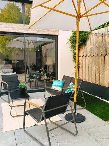 a patio with two chairs and an umbrella at Hang'Ares, espace unique entre Bassin et Océan in Arès