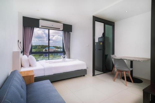 a bedroom with a bed and a couch and a window at Propify Central Serviced Residence in Ban Ket Ho