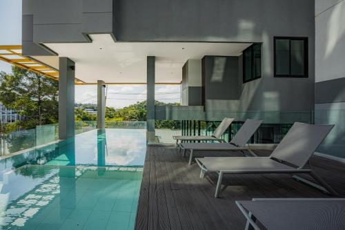 a swimming pool with lounge chairs and a house at Propify Central Serviced Residence in Ban Ket Ho